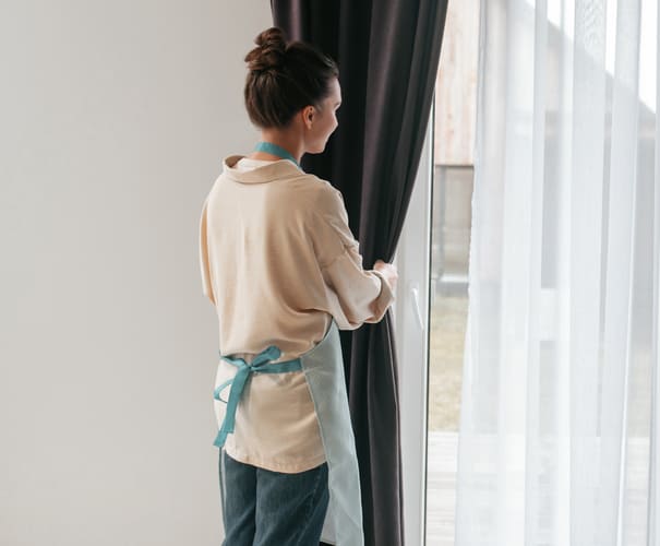 young-woman-standing-near-widnow-fixing-curtains (1)